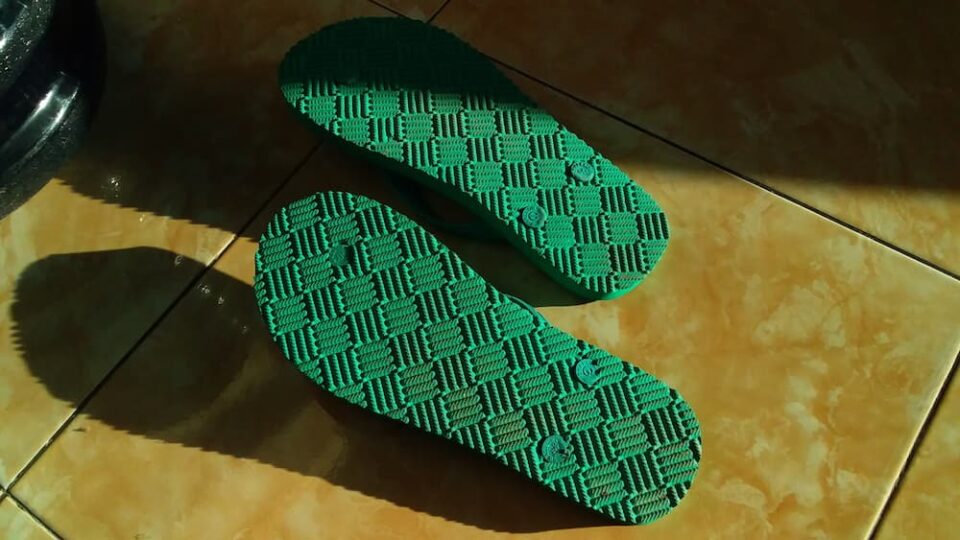 A pair of green sandals upside down on the floor