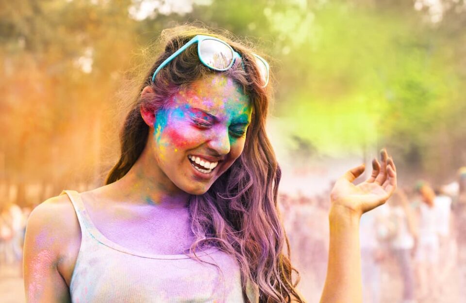 Person celebrating Holi with colored powder on her face