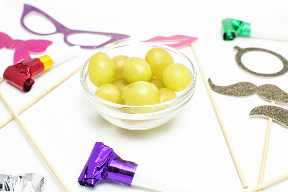A bowl of grapes surrounded by party favors