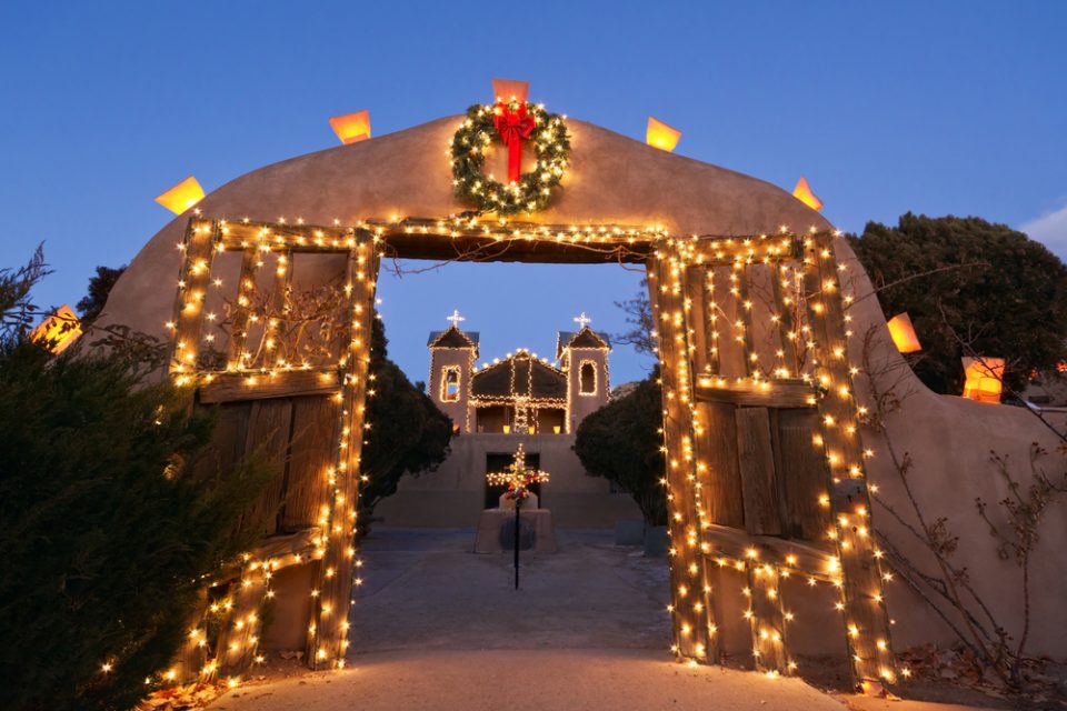 An archway with open doors decorated with Christmas lights and a wreath