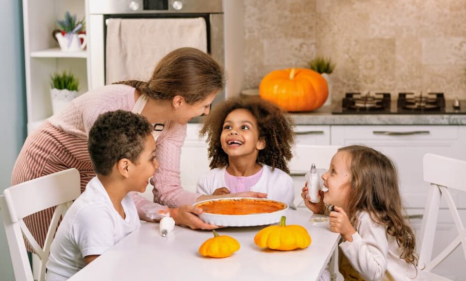 Family sitting down to eat pumpkin pie in the kitchen