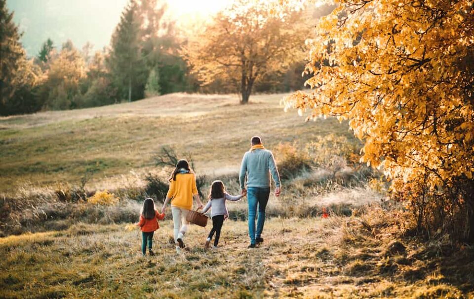 Family walking into field in fall for a picnic