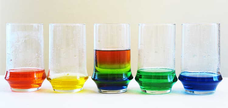 Five glasses of colored water at the end of the rainbow density experiment