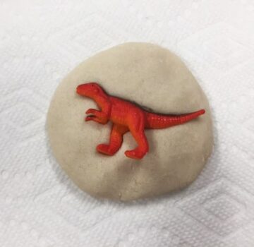 Red toy dinosaur pressed into salt dough