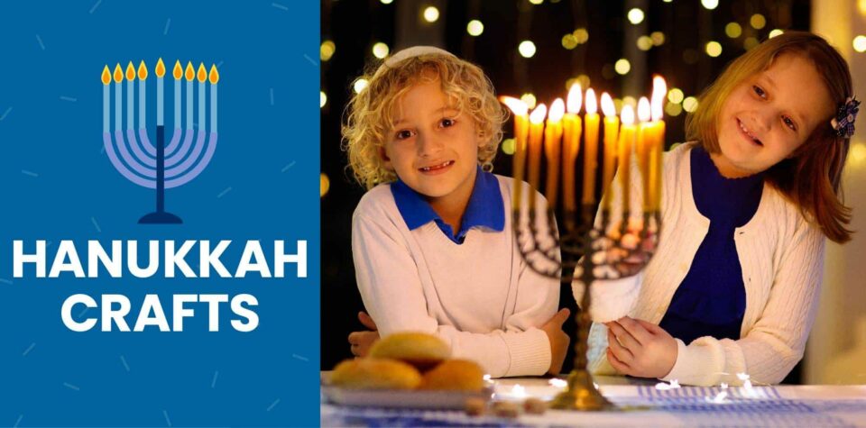 Two children in white and blue clothes smile in front of a menorah.