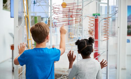 Two,Kids,Looking,At,A,Science,Exhibit,,Back,View