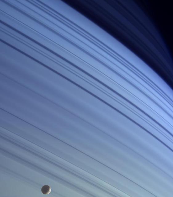 Blue bands in Saturn's atmosphere with its moon Mimas passing by