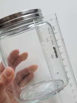 Person measuring side of mason jar