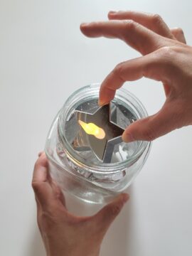 Person placing LED tea light into mason jar