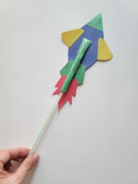 Person inserting straw into construction paper tube of straw rocket