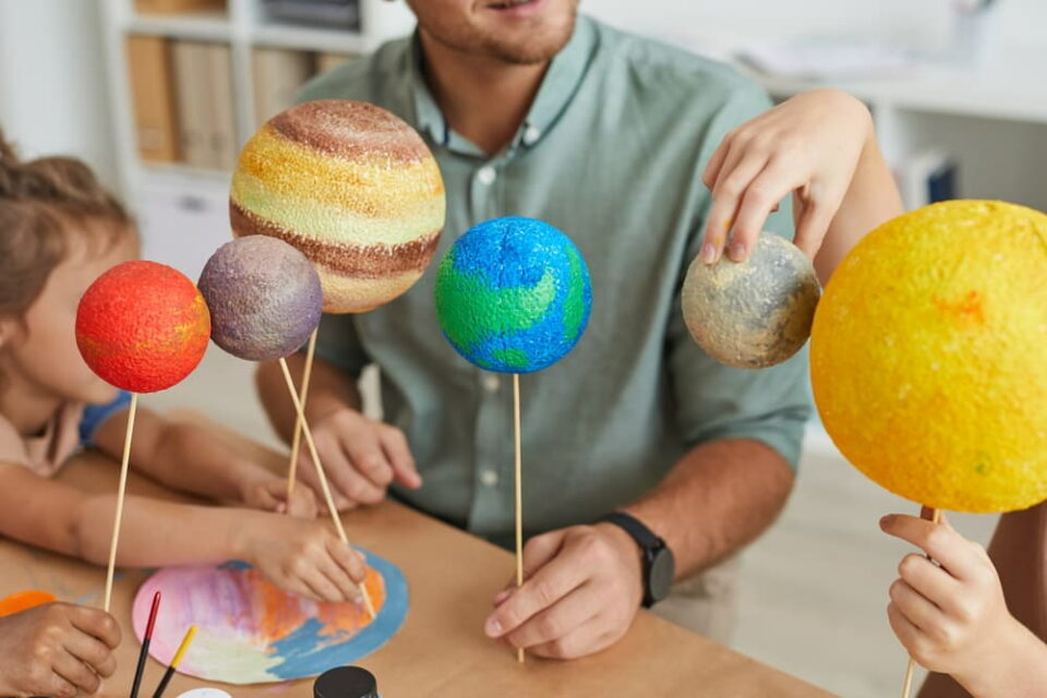 Adult and kids playing with models of the planets