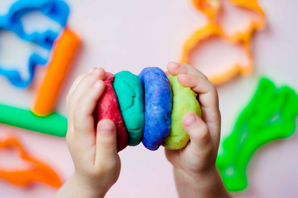 A-small-childs-hands-playing-with-different-colors-of-play-dough