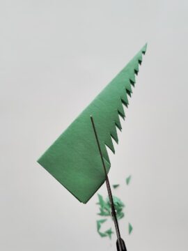 Scissors cutting a Christmas tree out of construction paper