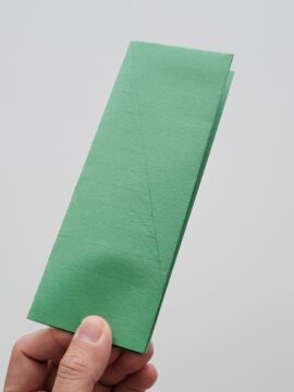 Folded construction paper with a Christmas tree drawn on it