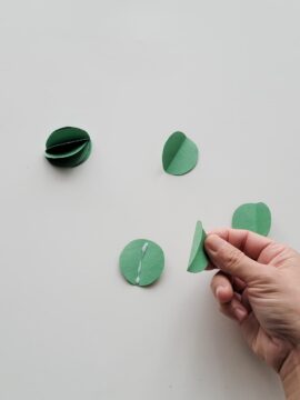 Person gluing folded Christmas ornaments together