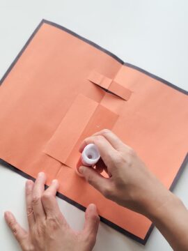 Hands gluing pop-up Halloween card together