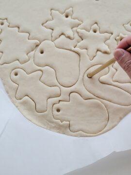 Person poking holes in unbaked salt dough ornaments