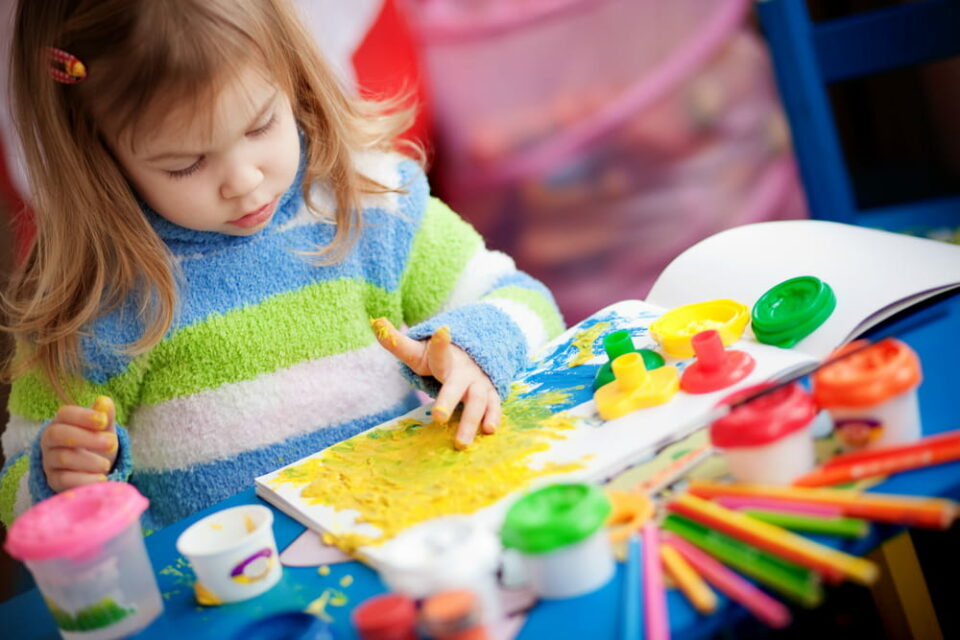 A little girl painting in her nursery at home.