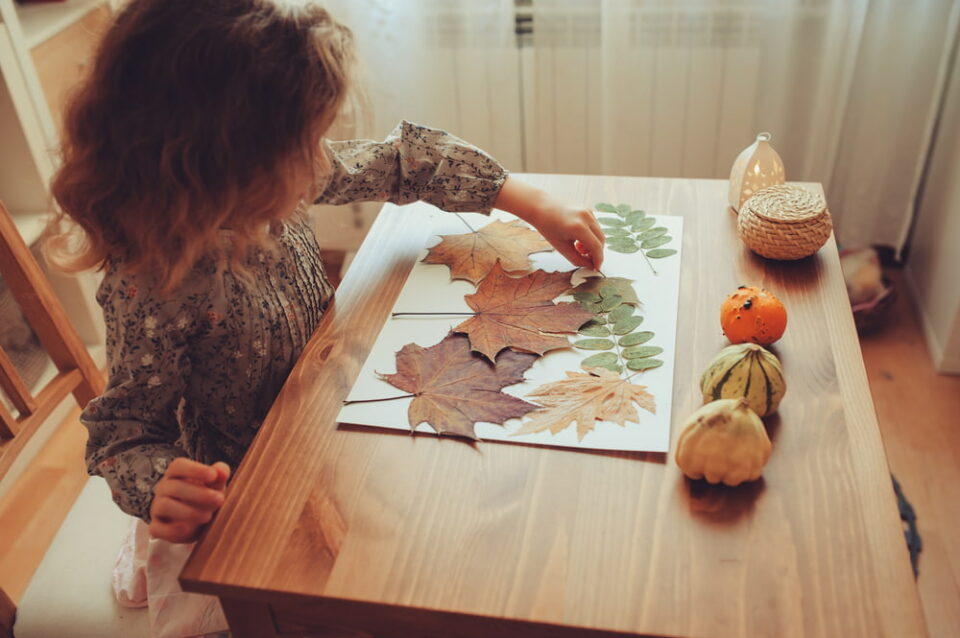 A-child-sits-at-a-table-creating-a-craft-using-fall-leaves