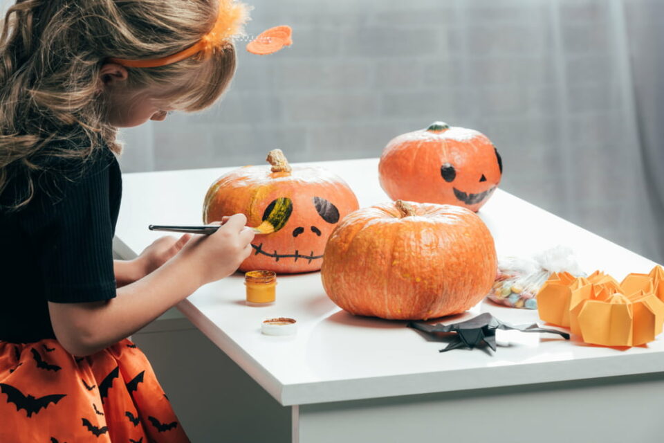 A young girl painting Halloween pumpkins