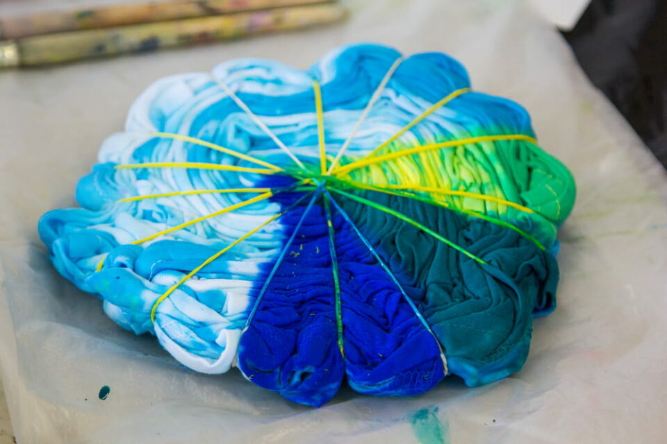 A piece of fabric tied with rubber bands and saturated with different colors