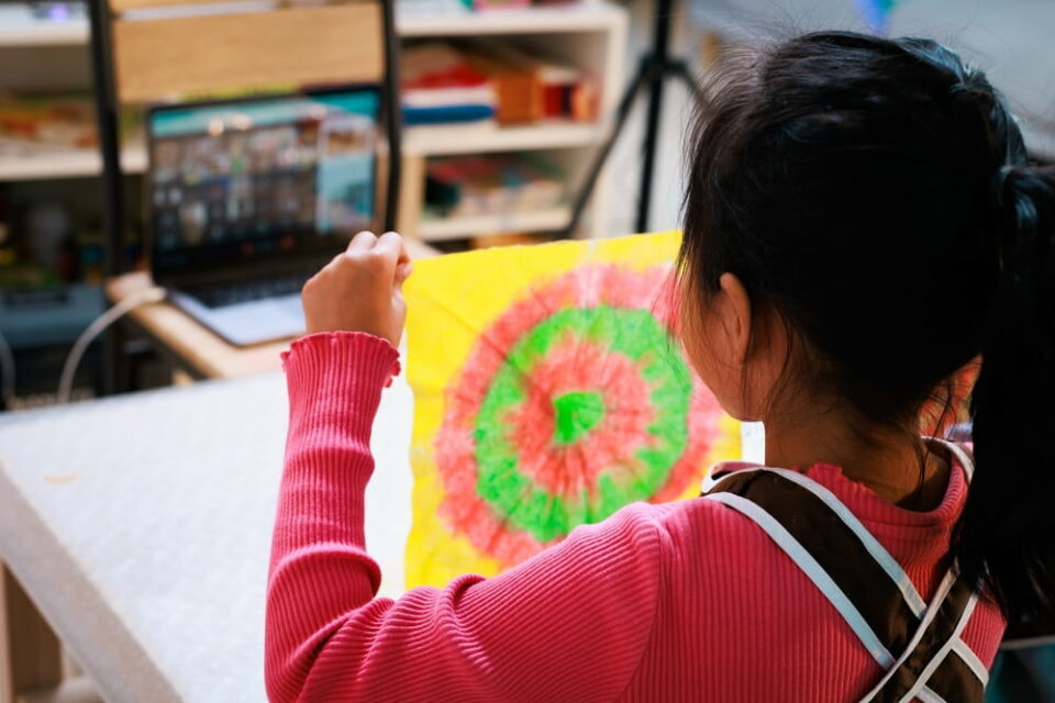 A young girl holds up a colorful tie-dyed piece of cloth
