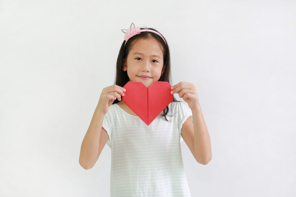 A girl holding a red paper heart
