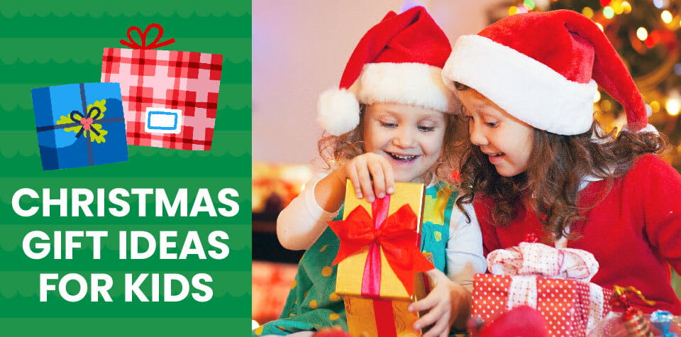 Two girls in Santa hats smile and look inside a Christmas gift box