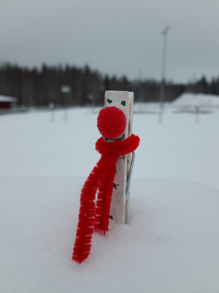 A DIY clothespin snowman craft pictured outside in the snow.