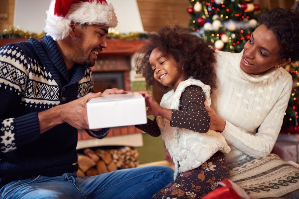 Parents and a young girl opening Christmas gifts