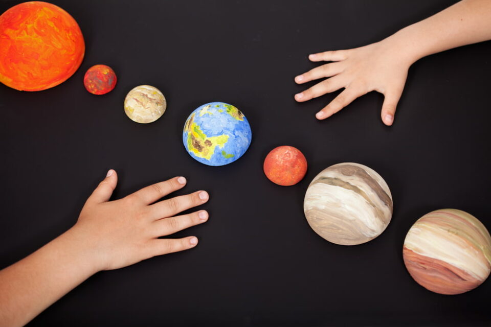 Kids-hands-placing-model-planets-in-a-line