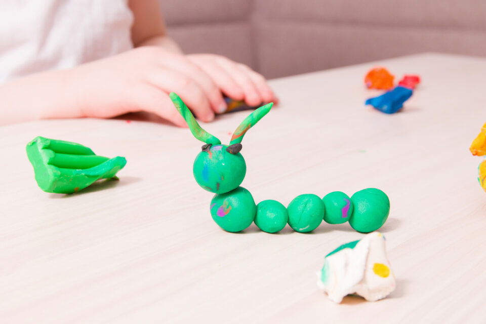 A green clay caterpillar on a table.