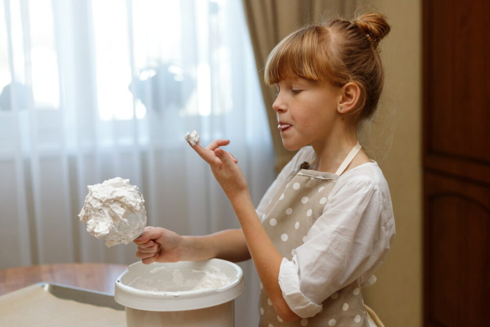 A young girl tasting the whipped cream she made