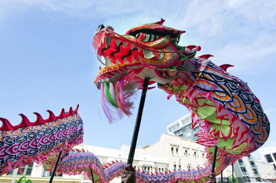 A colorful Chinese dragon puppet being carried on stilts