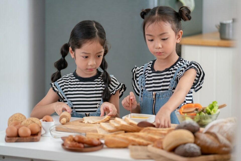 Girls-dipping-bread-slices-into-egg-and-milk-mixture-to-make-French-toast