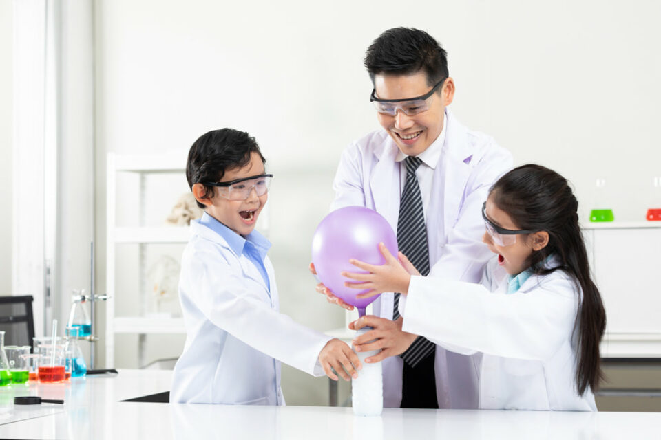 Two-children-and-adult-in-lab-coats-test-the-balloon-experiment