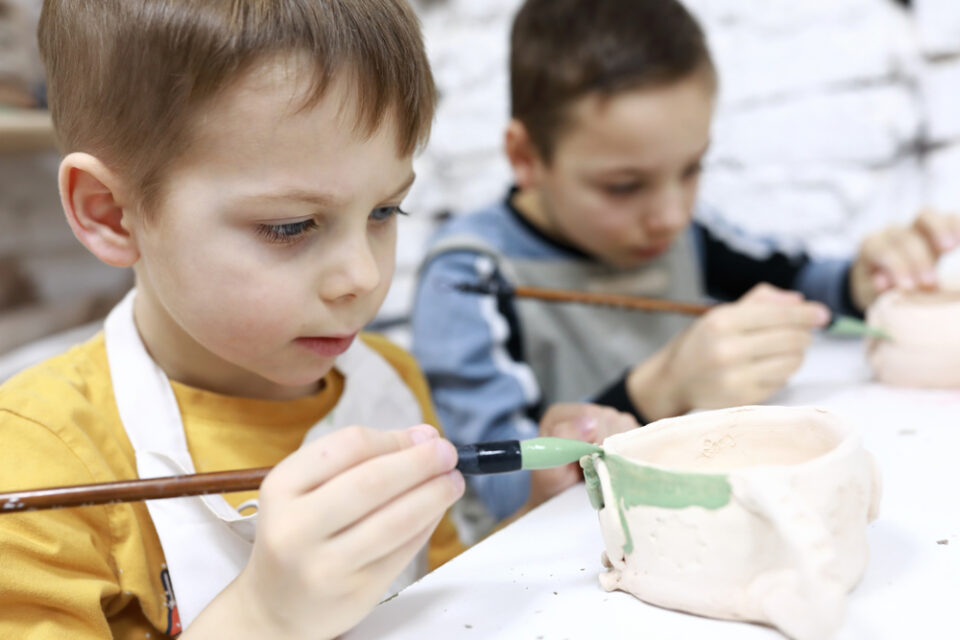 Two young boys paint their clay pinch pots.