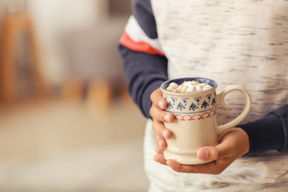 A boy holding a mug of hot chocolate.