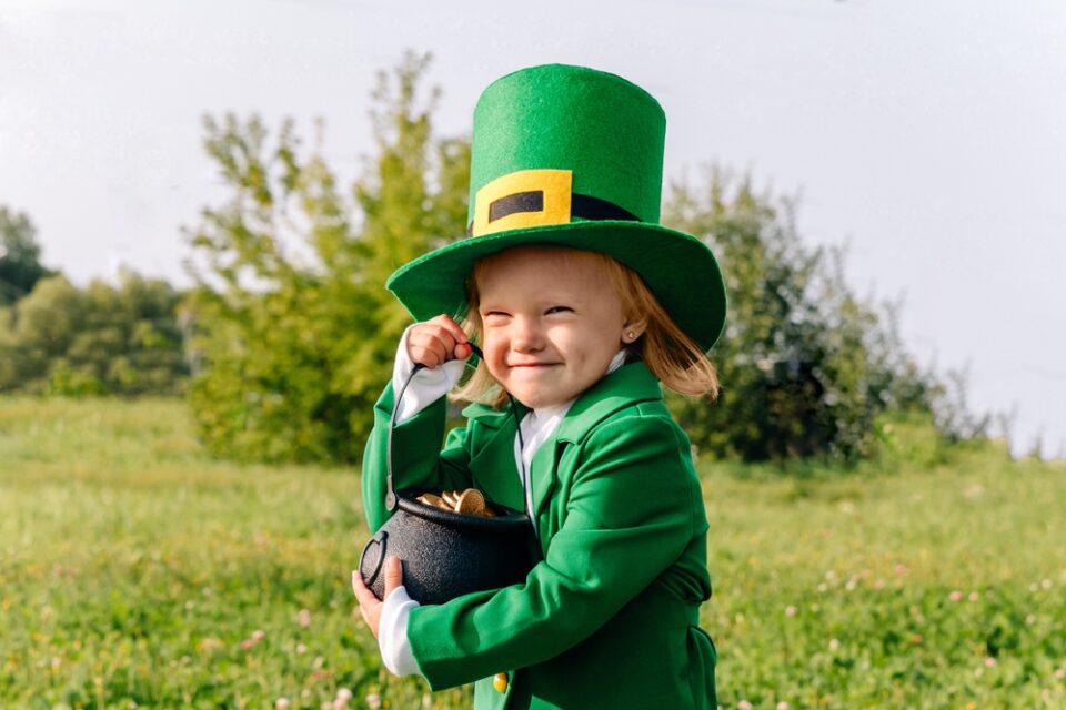 A child dressed as a leprechaun holding a pot of gold.