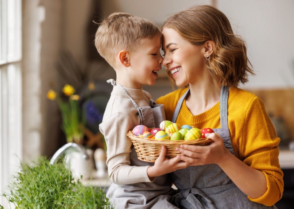 A mother and son hold a basket of Easter eggs.