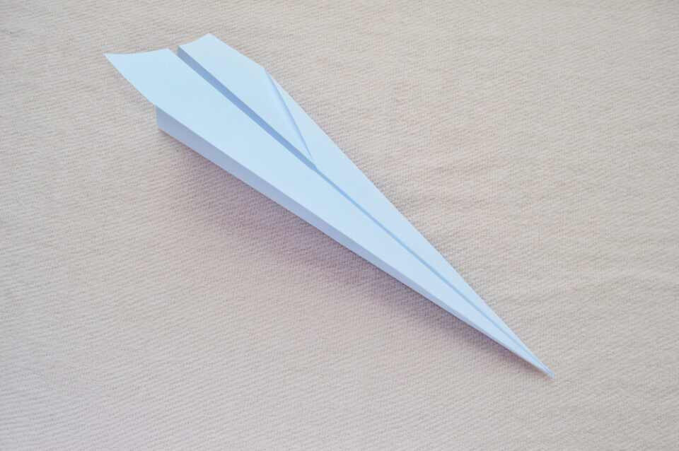 A paper airplane sitting on a light background.