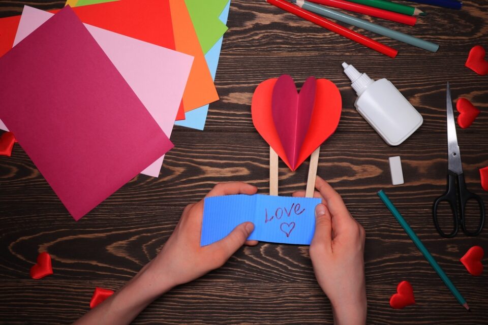 A paper heart balloon with a blue basket and the word “Love” written on it.