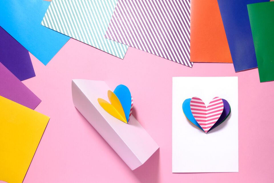 A white Valentine’s Day card with a multicolored 3D heart in the center