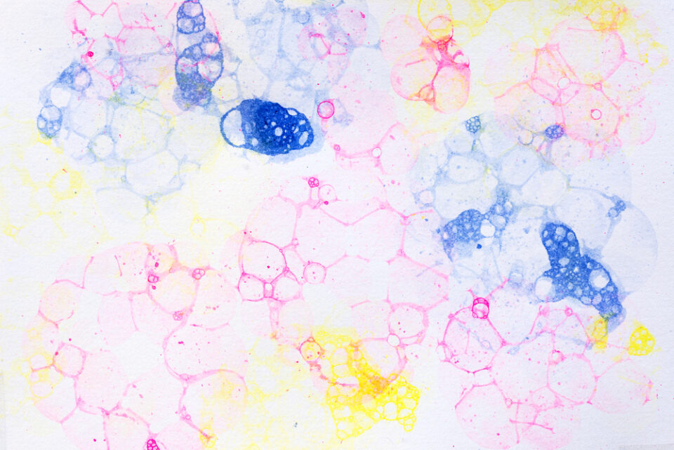 Blue, pink, and yellow bubble art on a white sheet of paper.