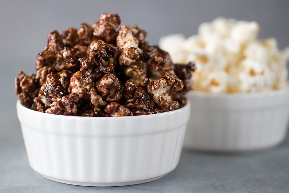 Chocolate popcorn and unflavored popcorn in white bowls.