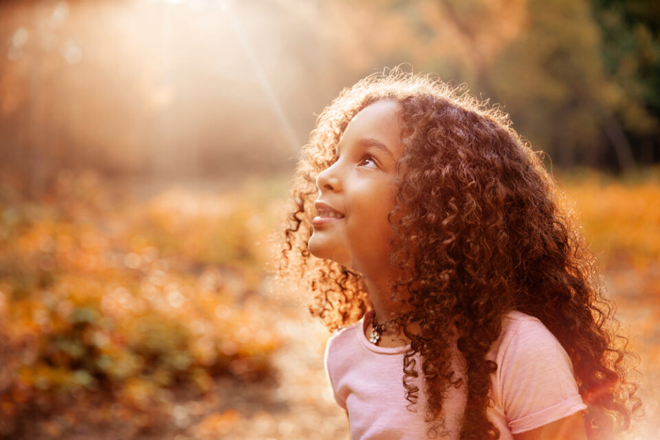 A young girl looking up at the Sun