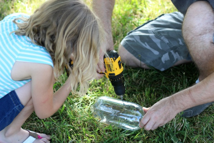 girl watching dad drill a hole