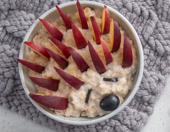 A bowl of oatmeal decorated with fruit to look like a hedgehog