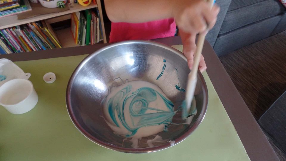 A child adding food coloring to their fluffy slime recipe