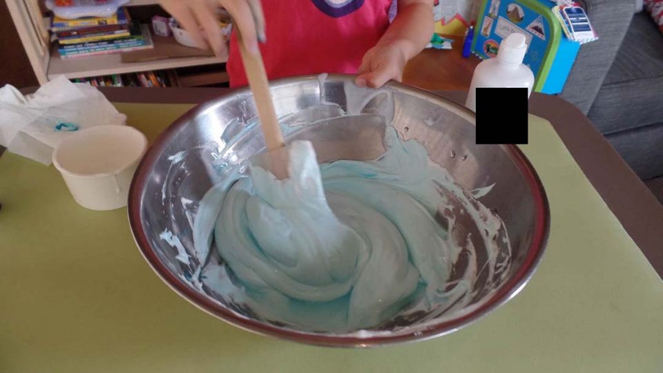 A child adding the slime activator to their fluffy slime mixture